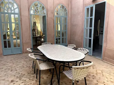 a table and chairs in a room with windows at Villa Blisina - Piscine privée & Petit-déjeuner inclus à Marrakech in Marrakech