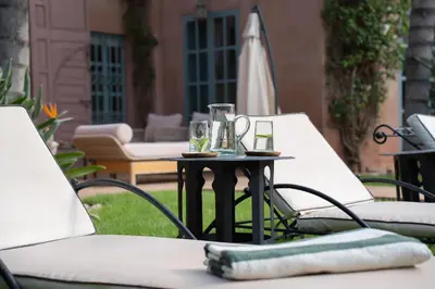 an outdoor table with two chairs and an umbrella at Villa Blisina - Piscine privée & Petit-déjeuner inclus à Marrakech in Marrakech