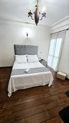 a bedroom with a large bed and a chandelier at Maison Ali in Ville Nouvelle