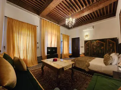 a bedroom with a bed and a table and a couch at Dar Zerbtana suite privative in Fès al Bali
