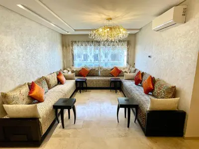 a living room with a couch and a chandelier at Appartement luxueux Prestigia Wifi Fibre Optique in Fès