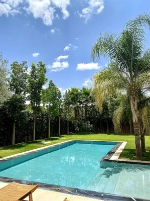 a swimming pool in a yard with a palm tree at Villa P1 avec Piscine Chauffée in Marrakech