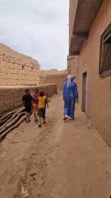 a group of children walking down a dirt road at Desert Mhamid Luxury Camp in Mhamid El Ghizlane