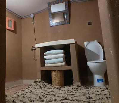 a bathroom with a toilet and a pile of towels at Desert Mhamid Luxury Camp in Mhamid El Ghizlane