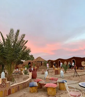 a desert setting with tables and chairs and people at Desert Mhamid Luxury Camp in Mhamid El Ghizlane
