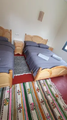 a bedroom with two beds and a rug at Tayda Guest House in Azilal