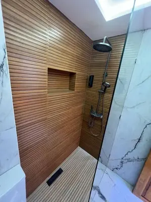 a bathroom with a shower with a wooden wall at Appartement Fes Sami Haut Standing in Fès