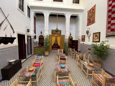 a room with tables and chairs in a building at Dar Zerbtana Chambre chaoune in Fès