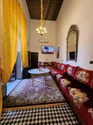 a living room with a red couch and a table at Dar Zerbtana Chambre chaoune in Fès