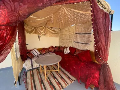 a room with a bed with a red couch and a table at Dar Zarbtana Chambre Hiba in Fès