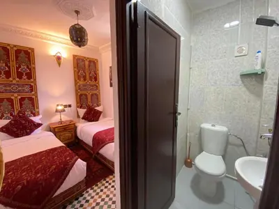 a bathroom with two beds and a sink and a toilet at Dar Zarbtana Chambre Hiba in Fès