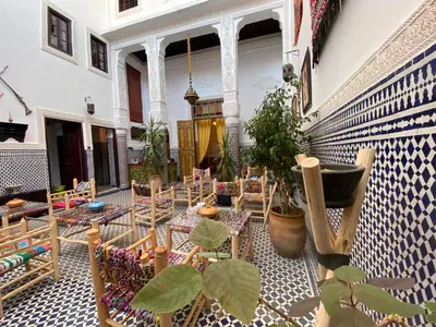 a courtyard with chairs and plants in a building at Dar Zarbtana Chambre RADIA in Fès