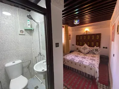 a bathroom with a bed and a shower and a sink at Dar Zarbtana Chambre RADIA in Fès