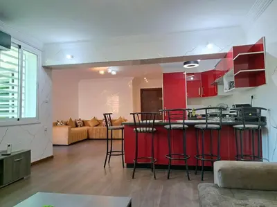 a kitchen with red cabinets and a bar in a living room at Appartement Jasmine Atlas Center in Fès
