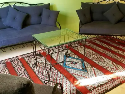 a living room with a table and a couch at KASBAH Jardin des délices Timalizen in Tamzerdirt