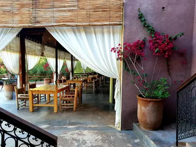 a restaurant with wooden tables and chairs and flowers at KASBAH Jardin des délices Timalizen in Tamzerdirt