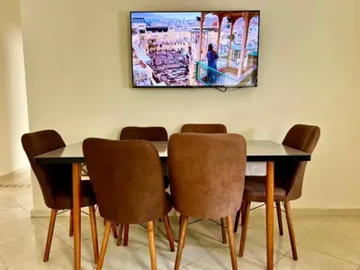 a dining room table with chairs and a tv on the wall at Appart Hotel Fes - Joud Families & Travelers in Fès