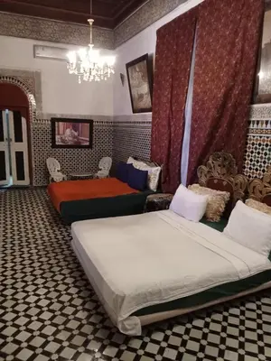 a bedroom with two beds and a chandelier at Double room in Fès