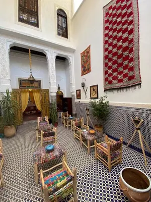 a living room with chairs and a rug on the wall at Dar Zarbtana Chambre Marrakech in Fès