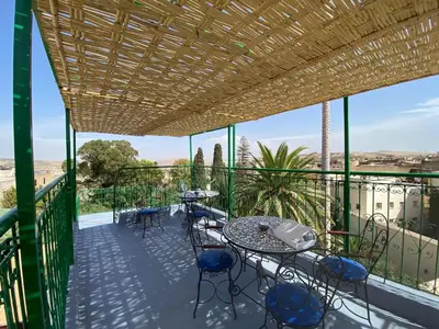 a patio with tables and chairs on a balcony at Dar Zarbtana Chambre Marrakech in Fès