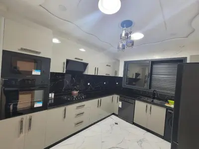a kitchen with white cabinets and black appliances at Bella nova in Azrou