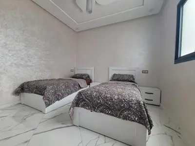 two beds in a bedroom with white walls and marble floors at Bella nova in Azrou
