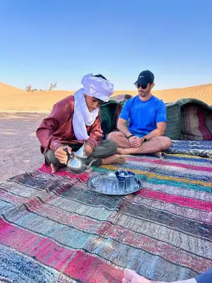 two people sitting on a rug in the desert at Sahara lumière in Mhamid El Ghizlane
