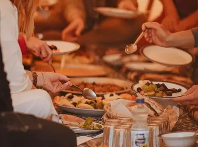 a group of people sitting around a table with plates of food at Sahara lumière in Mhamid El Ghizlane