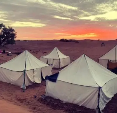 a group of tents in the desert at sunset at Sahara lumière in Mhamid El Ghizlane