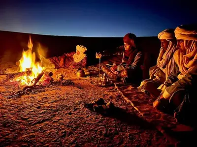 a group of people sitting around a fire at Sahara lumière in Mhamid El Ghizlane