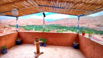 a balcony with potted plants and a view of mountains at Hostel Ighounane in Ouarzazate