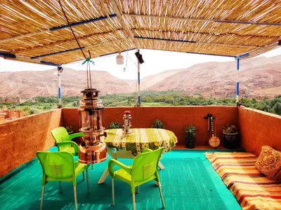a patio with a table and chairs and a view at Hostel Ighounane in Ouarzazate
