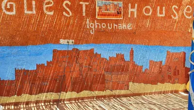 a wall with a painting of a city on it at Hostel Ighounane in Ouarzazate