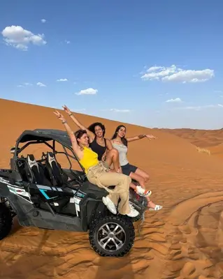 three women sitting on a wheeler in the desert at Chic Boheme Camp in Merzouga
