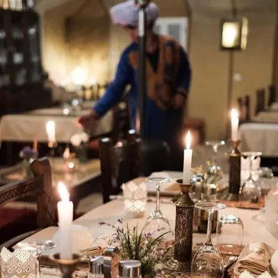 a man standing in front of a table with candles at Chic Boheme Camp in Merzouga