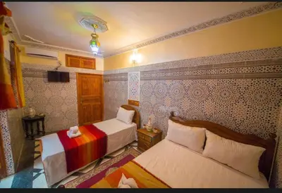 a hotel room with two beds and a tv at Riad Maison Haddaji Fez in Fès