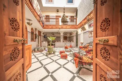 a room with wooden doors and a table and chairs at Riad Maison Haddaji Fez in Fès