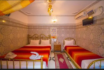 two beds in a bedroom with two swans on them at Riad Maison Haddaji Fez in Fès