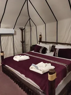 two beds in a tent with towels on them at Oasis Luxury Camp in Merzouga