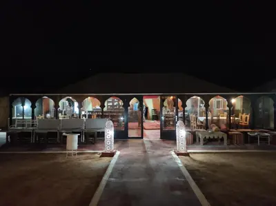 a tent with a table and chairs in the dark at Oasis Luxury Camp in Merzouga