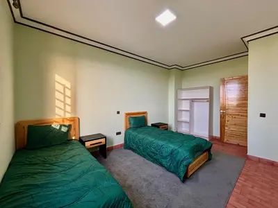 two beds in a room with green sheets at Cabanne ourika in Marrakech