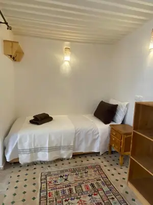 a bedroom with two beds and a table and a rug at Dar ZaZ in Fès