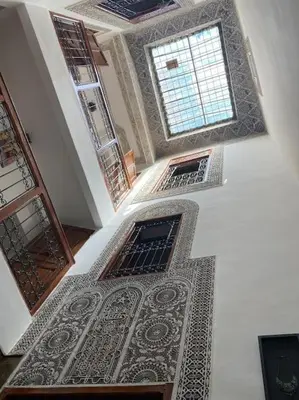 a hallway with a tile floor and windows in a building at Dar ZaZ in Fès