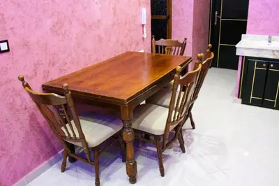 a wooden table and chairs in a room with pink walls at city fes in Fès