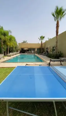 a blue ping pong table in front of a swimming pool at Villa P5 avec piscine chauffée in Marrakech