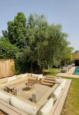a patio with white couches and a table and trees at Villa P5 avec piscine chauffée in Marrakech