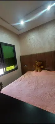 a teddy bear sitting on a bed in a bedroom at Mamoune benz in Fès