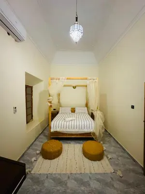 a room with a bed and two ottomans at Riad Kasbah Ben Hamo in Nkob