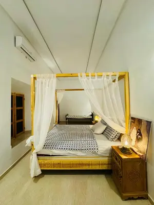 a bedroom with a canopy bed and a wooden table at Riad Kasbah Ben Hamo in Nkob