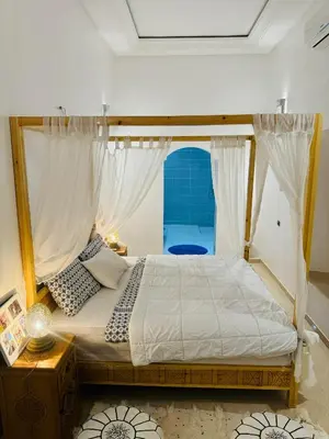 a bedroom with a canopy bed with a window at Riad Kasbah Ben Hamo in Nkob